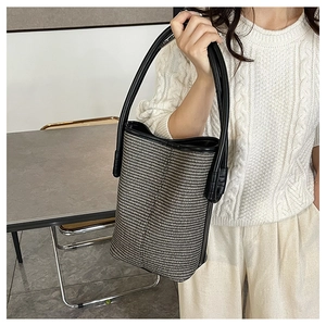 Close-up of woven bucket bag featuring black and white patterns with leather trim details
