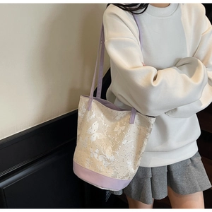 Detail of canvas bucket bag with butterfly pattern and purple contrast straps