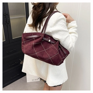 Detail of burgundy suede tote bag featuring white contrast stitching and soft texture