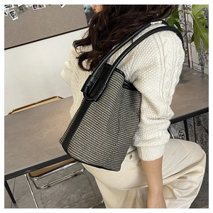 Fashionable woven bucket bag shown being worn over the shoulder by a woman in a knit sweater