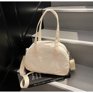 Detail of cream-white shell bag with wavy texture and brand logo on minimalist steps