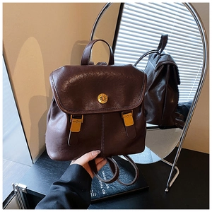 Detail of vintage brown leather backpack featuring a gold clasp and round mirror reflection