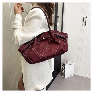 Detail of burgundy frosted suede tote bag with white contrast stitching and leather strap