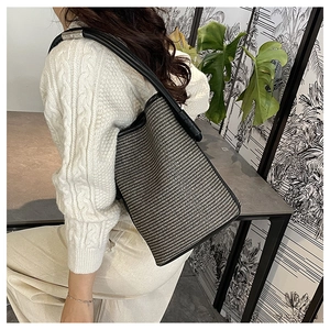 Detail of a black and white woven bucket bag with adjustable leather shoulder strap