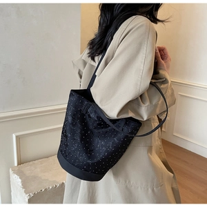 Dettaglio della borsa a secchiello nera con pois bianchi e tessuto jacquard strutturato