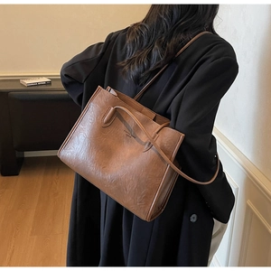 Brown textured leather tote bag showing carrying proportion and shoulder strap details