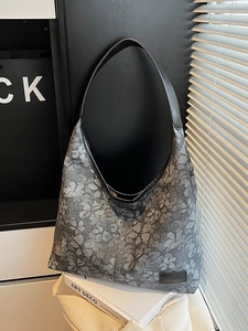 Large floral pattern hobo bag with black leather shoulder strap on white chair