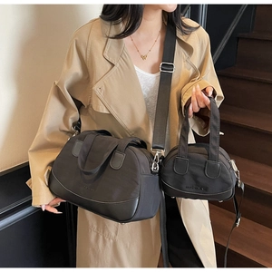 Detailed view of black nylon tote bag and mini shell handbag set on a model in urban style