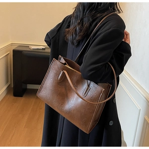 Close-up of deep brown leather tote bag with vintage texture and sleek metal zipper detail