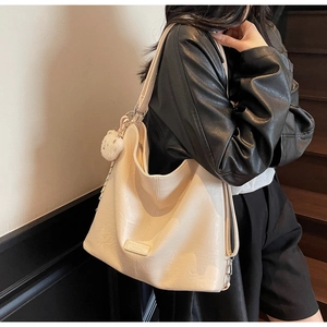 Close-up of off-white oversized tote bag with pleated leather texture and plush bear charm