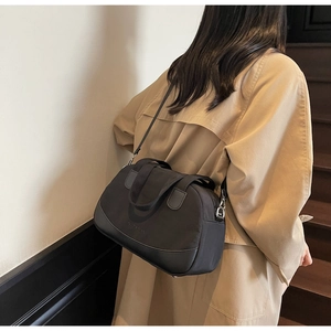 Detail of a black mini shell bag with NUOSIMAN logo shown in a casual commuter style