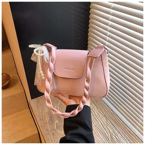 Detail of pink crossbody bag with woven handle and pearl lace bow charm decoration