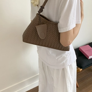 Dettaglio della borsa a secchiello in pelle intrecciata marrone con tracolla annodata