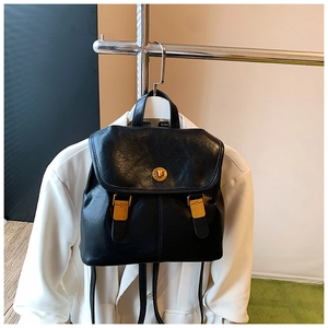 Detail of vintage black faux leather backpack with gold clasp and buckle straps