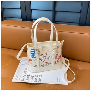 Vue détaillée du sac cabas blanc à graffiti avec texte positif et boucles dorées sur sofa