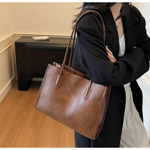 Close-up of vintage brown leather tote bag showing fine pleated texture and logo detail