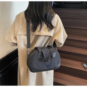 Fashionable black nylon mini shell bag with removable strap shown on model in street setting