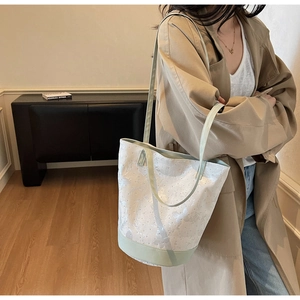 Detailed close-up of white lace texture and green leather trim on the bucket shoulder bag