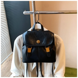 Detail of vintage black leather backpack with gold buckle and circular metal closure