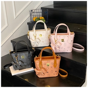 Detailansicht von vier Mini-Tragetaschen in Creme, Rosa, Schwarz und Karamell mit Bär-Prägung
