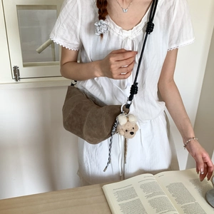 Vue détaillée du sac bandoulière en daim marron avec pendentif ours en peluche