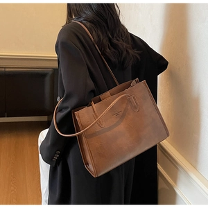 Close-up of brown matte leather tote bag featuring Fashion Trend WHTU text and slim straps