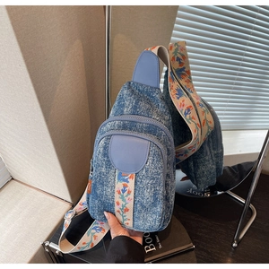 Detailed macro view of denim crossbody bag featuring ethnic floral embroidery strap