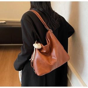 Detail of caramel brown Hobo bag texture with a cute white plush bear charm