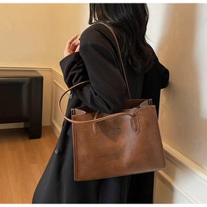 Detailed close-up of brown faux leather tote bag with embossed fashion trend text logo