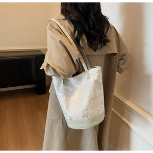 Chic butterfly print canvas tote bag with rivets and green leather base on model shoulder