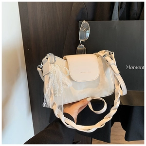 Detail view of cream white underarm bag with woven strap and pearl bow charm