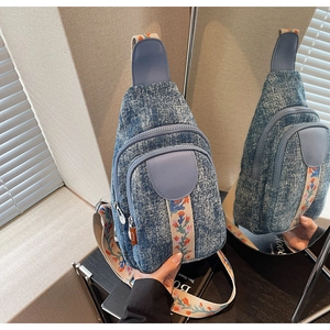 Detail of blue denim sling bag featuring vintage floral embroidered wide shoulder strap