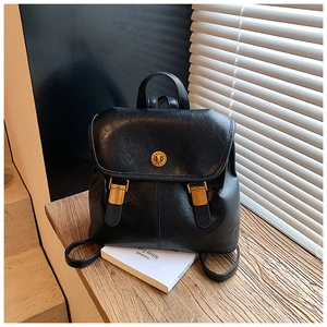 Detail of a vintage black leather backpack with gold circular lock and square buckles