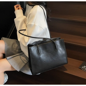 Close-up of black lychee texture tote bag on stairs showing its large capacity and strap
