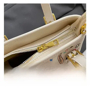 Détails de la fermeture éclair dorée et des ferrures sur un sac crème avec graffitis