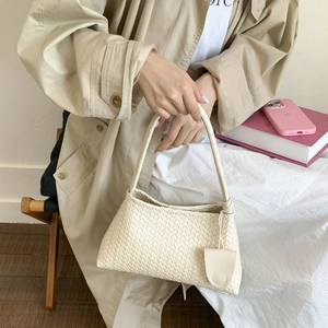 Dettaglio della borsa hobo intrecciata bianco crema con ciondolo portamonete coordinato