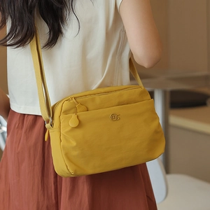 Detail of yellow nylon crossbody bag with multi-layer zippers and adjustable strap