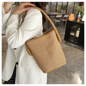 Detail of woven straw bucket bag showing brown leather strap and fine texture