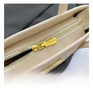 Detailansicht des goldenen Reißverschlusses und der geprägten Leder-Tote-Bag in Beige