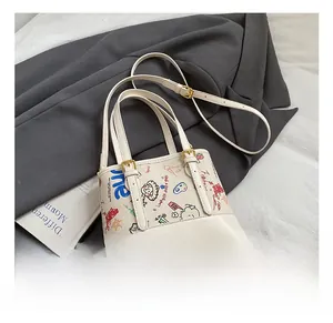 Détail de motifs graffiti colorés et bandoulière réglable sur le sac seau blanc