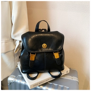Detail of vintage black leather backpack with gold hardware on a stylish travel background