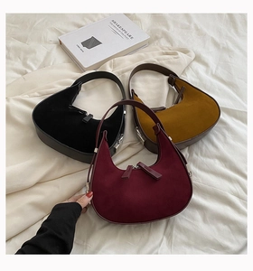 Detailed macro view of semi-circular underarm bags in suede and smooth leather finishes