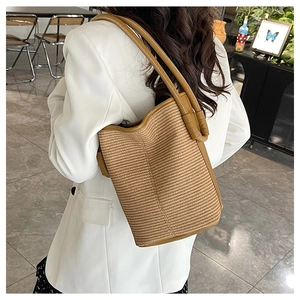 Detail of woven straw bucket bag with dark brown leather straps for seaside vacation