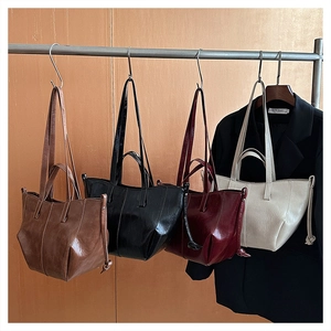 Detail view of four vintage faux leather tote bags in brown, black, burgundy, and off-white