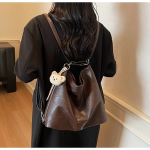 Detail of vintage dark brown leather tote showing adjustable straps and plush bear charm