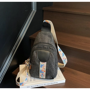 Detail showing high-quality gray denim texture and colorful embroidered strap of the bag
