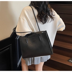 Black large tote bag with embossed text detail on matte leather surface