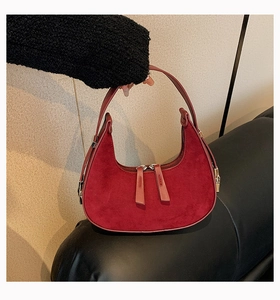 Detailed macro view of burgundy suede hobo bag with leather handle and dual silver zippers
