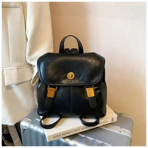 Detail of vintage black leather backpack showing gold twist lock and smooth texture
