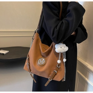 Dettaglio della borsa tote in nylon caramello con logo M e ciondolo a nuvola di peluche